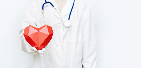 Medicine doctor woman in white coat with stethoscope holds red heart. Healthcare and medical concept.