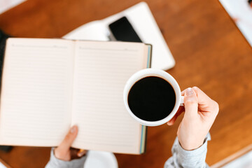 young relaxing woman hold cup of coffee and reading a book at home.