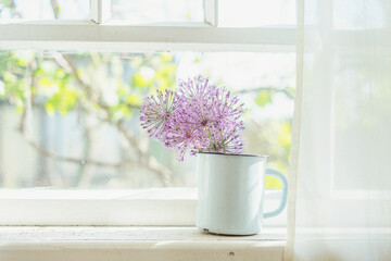 Wild onion flower on the windowsill of an abandoned summer house.