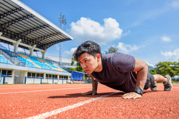 man doing push ups on track race at sport stadium in the morning.