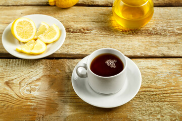 Obraz na płótnie Canvas White cup with tea with lemon and honey on the table.
