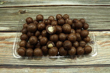 Pile of baked fresh organic macadamia nuts on the plastic tray. Famous appetizer snack in the party. Luxury nuts with high nutrition and power. 