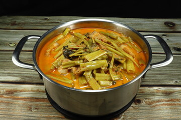 Spicy Thai red curry soup with cutting fresh morning glory, chopped streaky pork , chilly paste and coconut milk in the aluminium pot. Famous traditional hot soup in Thailand. 