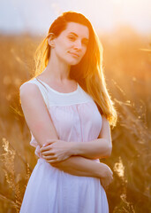 Beautiful brunette lady in wheat field at sunset
