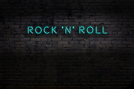 Neon sign. Word rock 'n' roll against brick wall. Night view