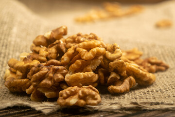 Peeled walnuts in bulk on a wooden table covered with rough-textured burlap. Healthy diet. Fitness diet. Close up.