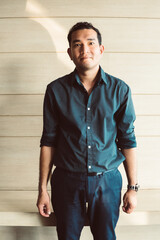 Young businessman asian smiling and looking at camera. Portrait of a happy handsome young man on wooden background. Close up face of young cool trendy man looking at camera