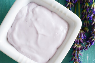 lavender soaps and cosmetic cream, flowers on blue wooden table