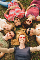 Friends having fun together in the park. Young people are lying on the grass