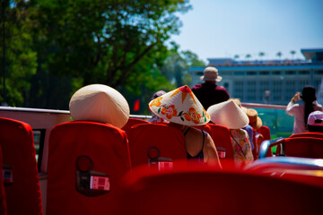 Tourists wearing vietnamese hat at the top roof of double decker bus in Ho Chi Minh