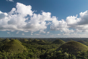 Chocolate hills on a sunny day with blue sky and clouds. Truffle shaped formations is the main attraction of Bohol island, Philippines