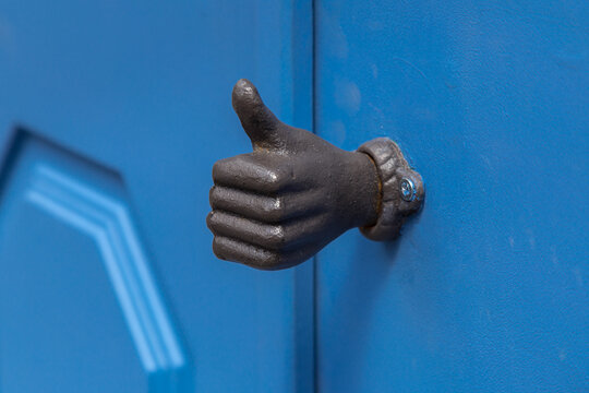 Old metal door handle in a form of a hand with thumb up