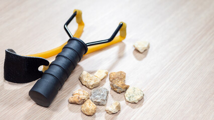 Slingshot small hand-powered projectile weapon with stone and rock. Y-shaped frame held in off hand...