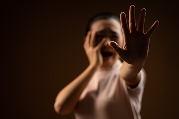 Asian woman scared screaming covering face by her hands standing isolated on beige background.
