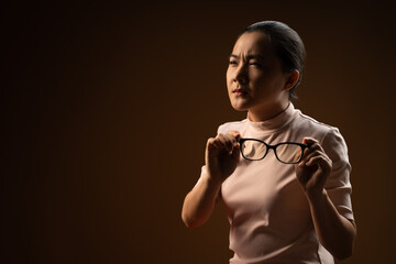 Asian woman was sick with eyes pain standing isolated on beige background.