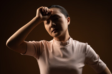 Asian woman was sick with headache standing isolated on beige background. Low key.