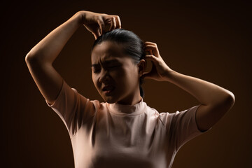 Asian woman scratching her head, standing isolated on beige background.