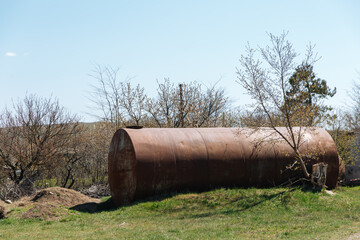 Two old abandoned rusty barrels lie in the open air on the grass