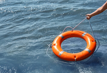 Woman throwing lifebuoy ring on water