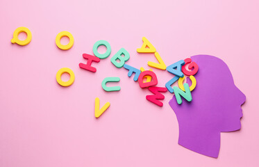Paper human head with letters on color background. Dyslexia concept