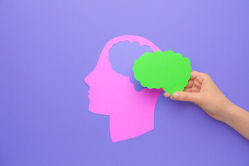 Female hand with paper brain and human head on color background. Neurology concept