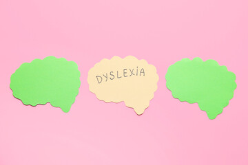 Paper brains with word DYSLEXIA on color background