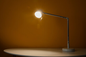 Fototapeta na wymiar Glowing lamp on table in dark room