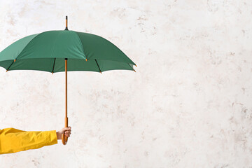 Hand with stylish umbrella on light background