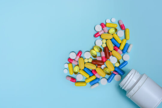 White bottle with colorful capsules, vitamins, supplements, pills in the form of a heart. Medicines for the treatment of heart disease.Copy space for text.