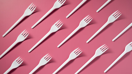 DIAGONALLY: Many plastic forks on a pink background. Top view - 359357356