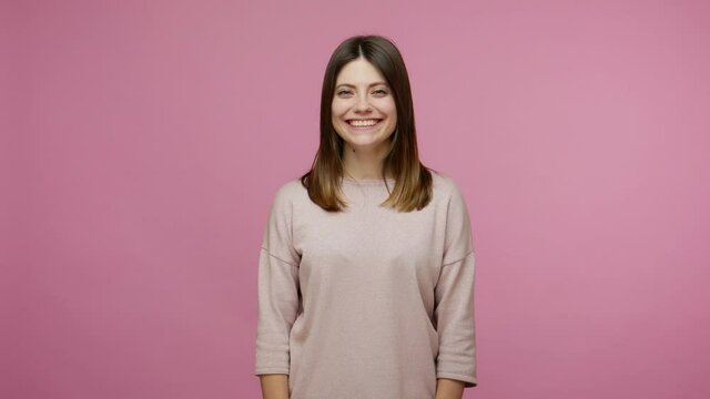 Hearing loss. Woman communicating with deaf-mute sign language, welcoming with friendly smile and making fingers shape saying nonverbal phrase Nice to meet you. studio shot isolated on pink background