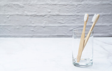 A toothbrush in a cup set against a marble background.