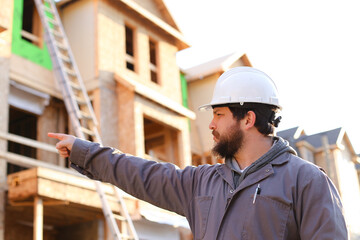 Adult foreman and engineer giving indication on construction site and wearinhg hardhat.