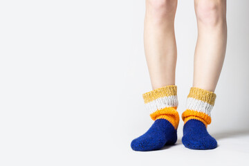 Female legs in warm multi-colored socks on a light background