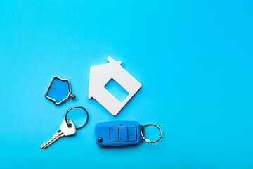 Keys from house and car on color background