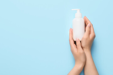 Hands of young woman with cream on color background