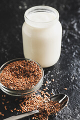 Jar of yogurt and flax seeds on dark background