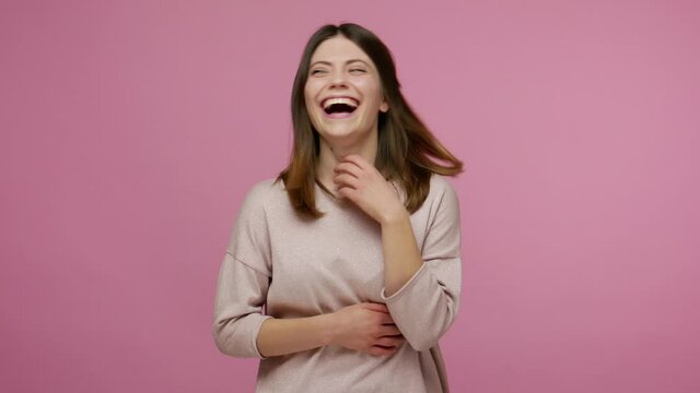 Delighted brunette carefree young woman amused by really funny joke, holding her stomach and laughing out loud, being hysterical at hilarious anecdote. indoor studio shot isolated on pink background