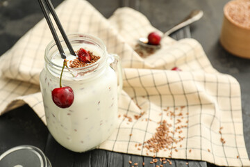 Mason of yogurt with berry and flax seeds on dark background