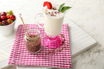 Glass cup of yogurt with strawberry and flax seeds on table