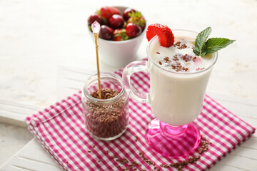 Glass cup of yogurt with strawberry and flax seeds on table