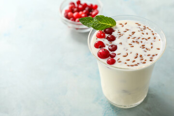 Glass of yogurt with berry and flax seeds on color background