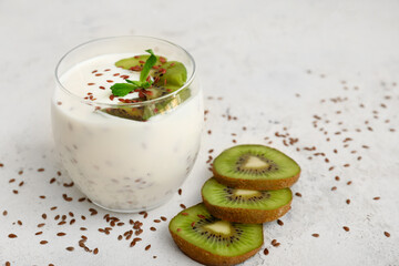 Glass of yogurt with kiwi and flax seeds on white background