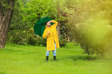 Young man with umbrella wearing raincoat outdoors