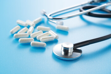 Stethoscope and pills on a blue background.