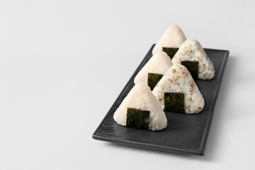 Plate with traditional Japanese onigiri on grey background