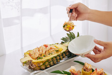 Close-up image of woman putting fried rice with vegetables and shrimps into small bowl