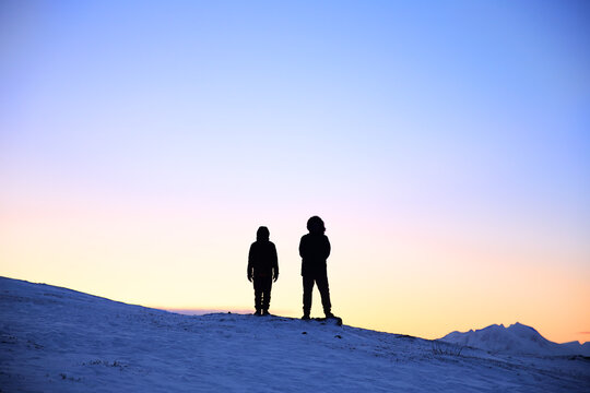 silhouette of people standing on a mountain top