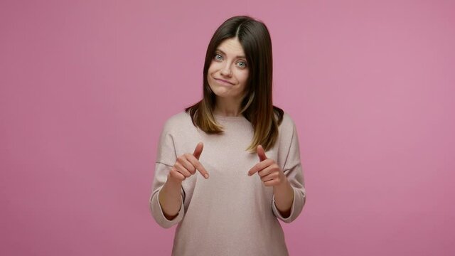 Come here to me right now! Bossy brunette young woman pointing down with angry expression, controlling and demanding to do immediately, giving command. indoor studio shot isolated on pink background