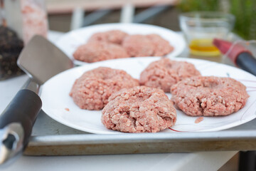 A view of several raw burger patties on a plate, ready for grilling.